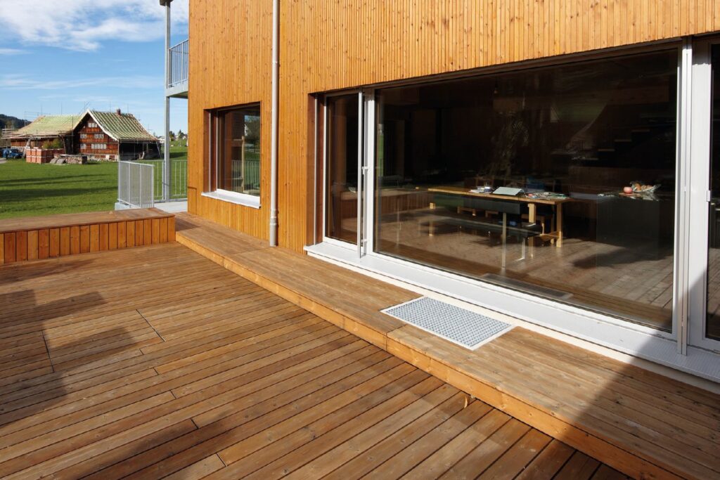 Holzterrasse aus thermobehandelter Kiefer vor einem Holzhaus